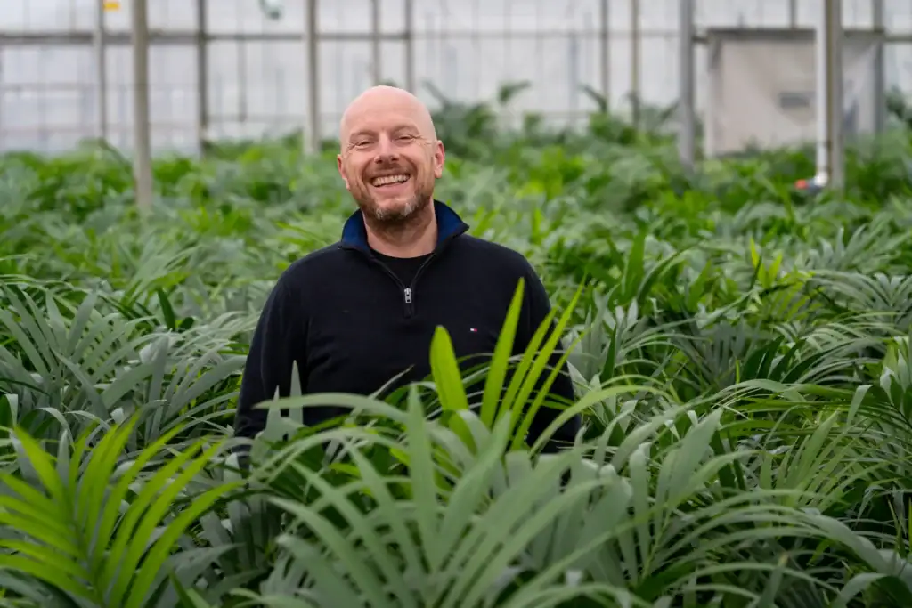 Christian Blom, trotse mede-eigenaar van Blom KENTIA Palmen, poseert tussen de Kentia's in de kas